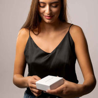 Thumbnail for Woman opening a gift box, excited to reveal the Love Photo Necklace by Brother & Sisters.