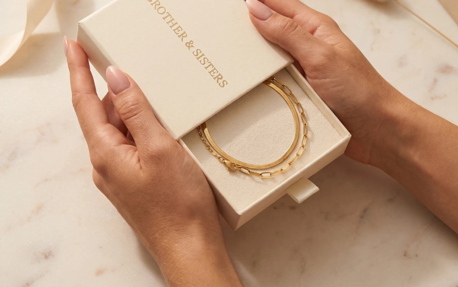 Gold anklets in an open Brother & Sisters gift box