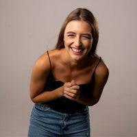 Thumbnail for Smiling woman wearing a black top and jeans, showcasing joy and happiness in a studio setting.
