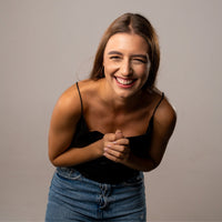 Thumbnail for Smiling woman wearing a black top and denim skirt, showcasing joy and warmth in her expression.