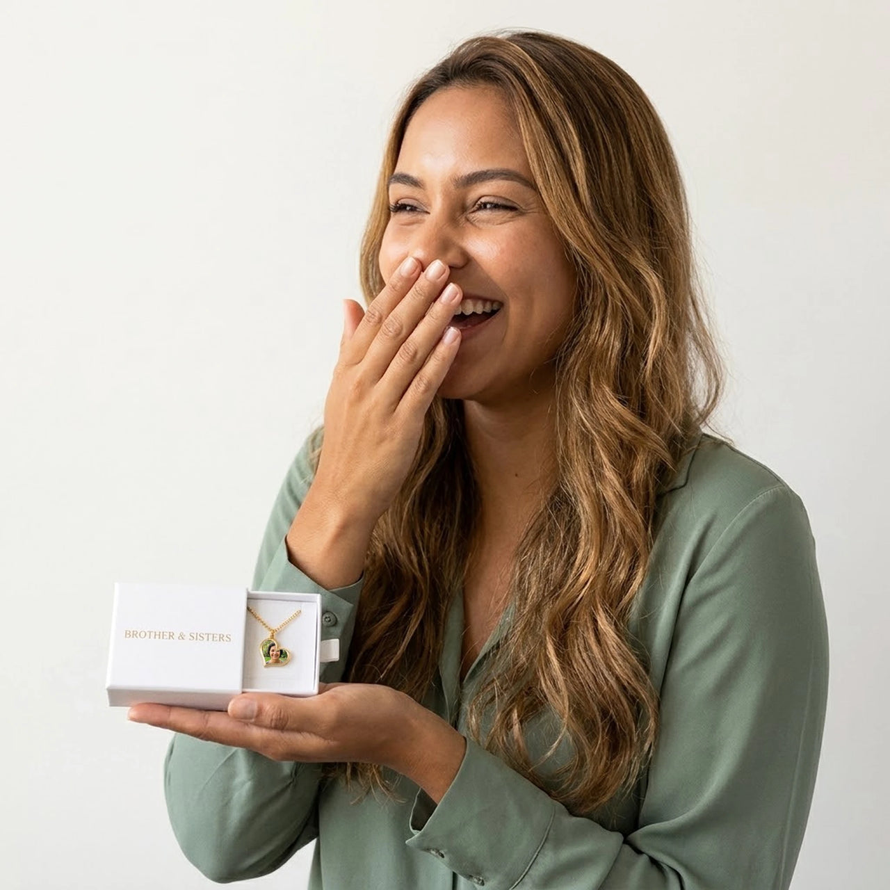 Woman laughing with joy as she discovers her mother's photo in the gold heart necklace, in the Brother & Sisters gift box | SKU: TPH-HRTN-GOLD