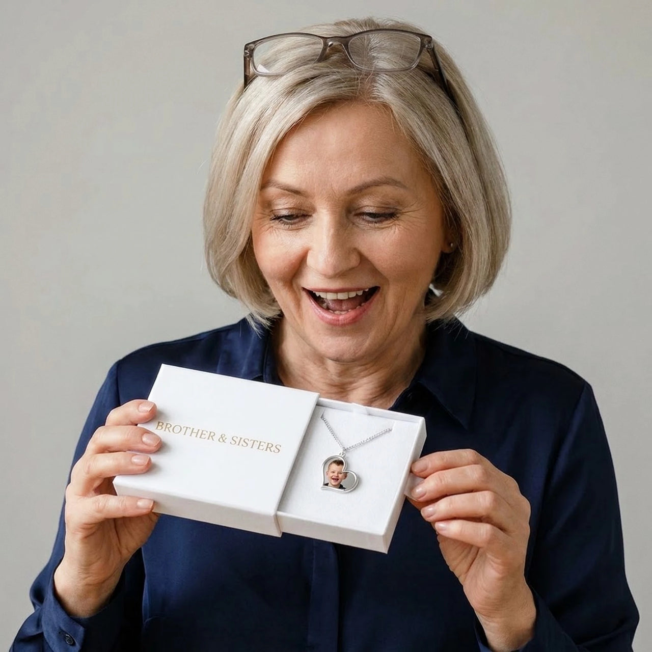 Woman in her fifties discovering her grandson's photo in the silver heart necklace, in the gift box | SKU: TPH-HRTN-SILVER