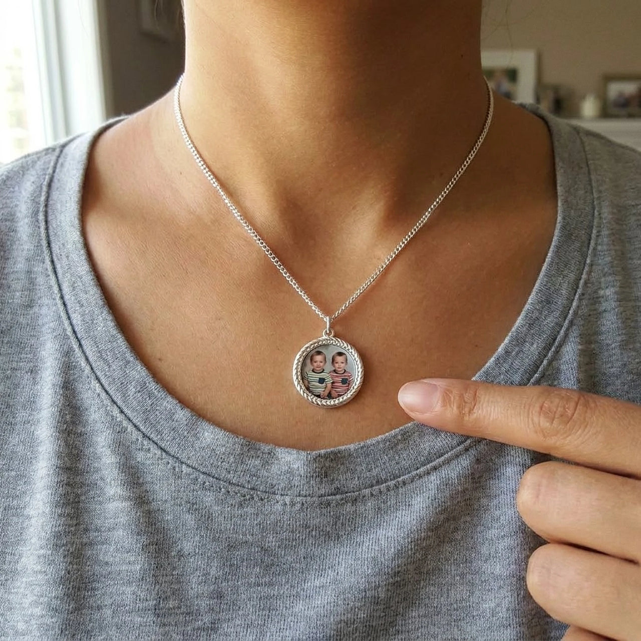 Looking down at the silver round pendant next to her fingertip, real small size, twins' photo inside | SKU: TPH-RNDN-SILVER