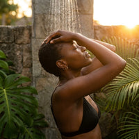 Thumbnail for Tiny Huggie Hoops in Gold, worn in a tropical outdoor shower | SKU: 41002-gold